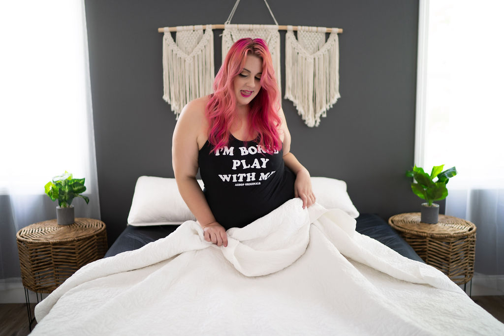 woman in black tank top playing in a a white bed with pink hair Viselli Salon